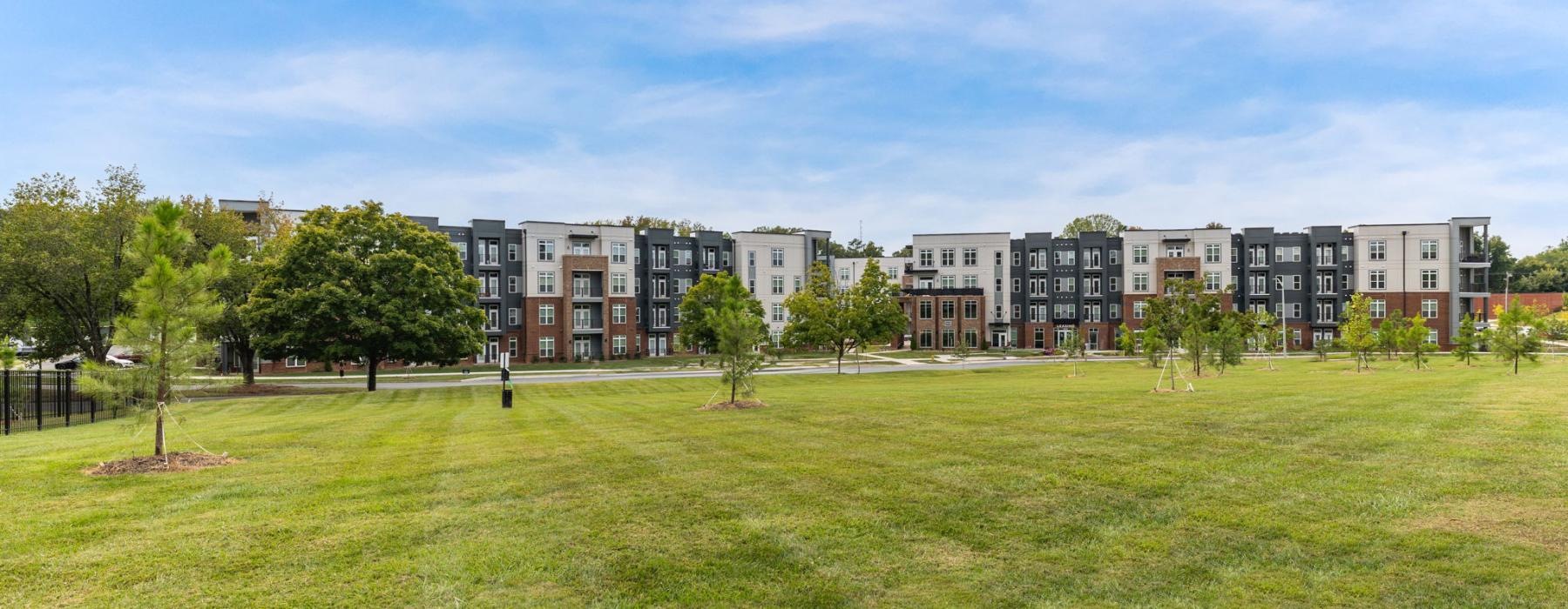 a grassy area with trees and buildings in the background